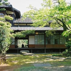 a person sitting on a bench in front of a building with lots of trees around it