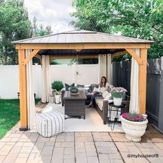 a woman sitting on top of a couch under a gazebo next to a table and chairs