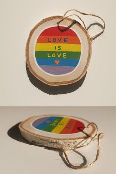 a piece of wood with the words love is love painted on it and tied to a string