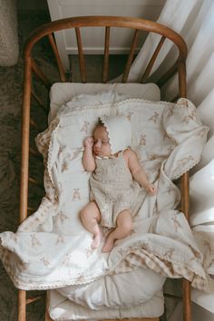 a baby is laying in a crib with white sheets