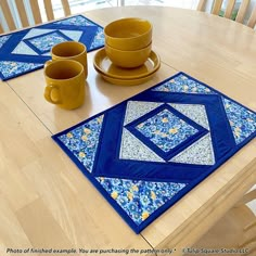 a wooden table topped with two cups and a plate covered in blue quilted material