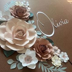 some paper flowers are laying on top of a brown card with the word ouvia