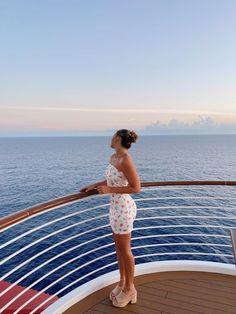 a woman standing on the deck of a cruise ship looking out at the ocean and clouds