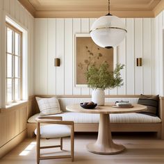 a living room with white walls and wood paneling on the wall, a round table surrounded by two chairs