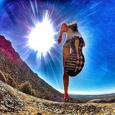 a woman is running down a trail with the sun in the background