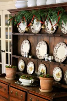 an old china cabinet with christmas decorations and plates on the top shelf in front of it