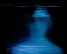 a blurry image of a person standing in the dark with their head turned to the side