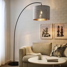 a living room with a couch, coffee table and floor lamp in the corner on the wall