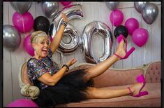 a woman sitting on top of a couch in front of balloons and helium letters that spell out the word boo