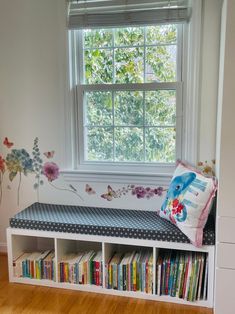 a room with a window, bookshelf and flowers on the wall