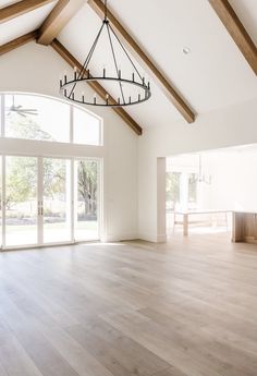 an empty living room with wood floors and large windows