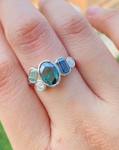 a woman's hand holding a ring with two blue stones and diamonds on it