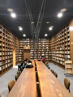 an empty library with many bookshelves and people sitting at long tables in front of them