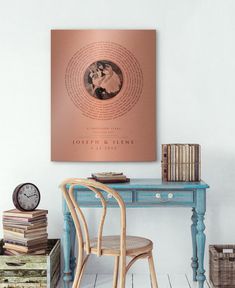 a desk with a chair, clock and books on it in front of a white wall