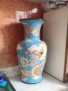 a large blue vase sitting on top of a counter next to a wall mounted refrigerator