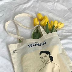 a tote bag with yellow flowers in front of it and the words woman on it