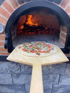 a pizza is being cooked in an outdoor oven