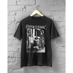 a black t - shirt with the band fleetwood on it hanging against a brick wall