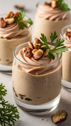 three desserts in small glass dishes with nuts on top and garnished with green leaves