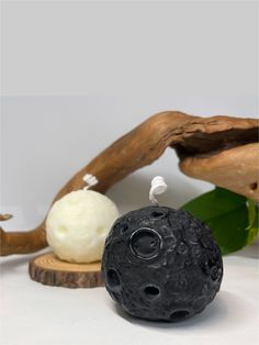 two soap balls sitting next to each other on top of a wooden stand with green leaves