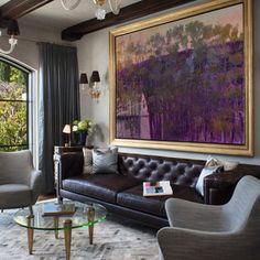 a living room filled with furniture and a large painting hanging on the wall above it