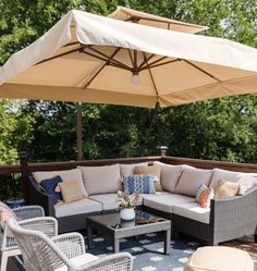 an outdoor living area with couches, tables and umbrellas on top of it