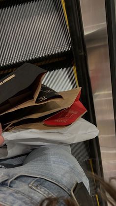 a person sitting on a bus with some bags in their lap and one hand holding a cell phone