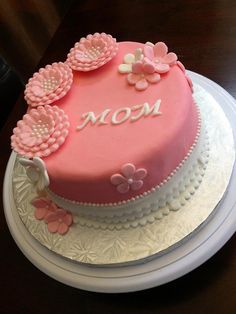 a pink cake decorated with flowers and the word mom