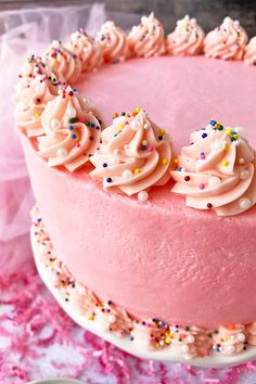 a pink frosted cake with sprinkles on top