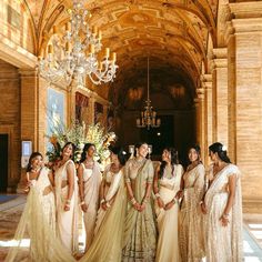 a group of women standing next to each other in front of a chandelier