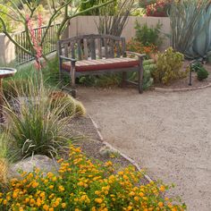 a bench sitting in the middle of a garden next to flowers and plants on either side of a fence