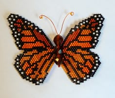 an orange and black beaded butterfly on a white surface