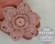 a crochet flower is being held in the palm of someone's hand