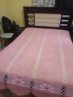 a pink crocheted bedspread on top of a bed