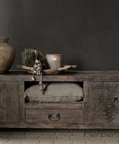 an old wooden table with two vases on it and a pillow in the middle