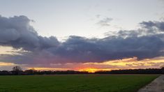 the sun is setting over an open field