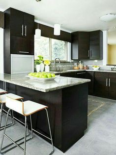 a kitchen with black cabinets and white counter tops, two stools in front of the island