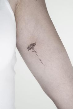 a woman's arm with a single flower tattoo on the left side of her arm