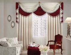 a living room filled with white furniture and red drapes on the windowsills