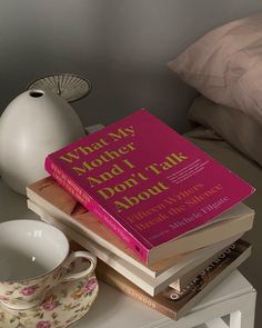 a stack of books sitting on top of a table next to a cup and saucer