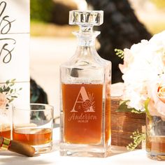 a bottle of alcohol sitting on top of a table next to two glasses and a sign