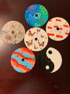 six buttons with different designs on them sitting on a wooden table next to each other