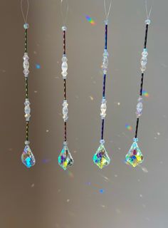 four crystal necklaces hanging from strings in different colors and shapes, with light shining on them