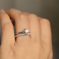 a woman's hand with a diamond ring on top of her finger and an engagement band