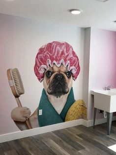 a pug dog wearing a pink hat and holding a brush in front of a wall mural