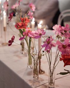 several vases filled with pink and red flowers on a white table cloth covered table