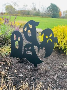 a metal sign with two faces on it sitting in the middle of some dirt and grass