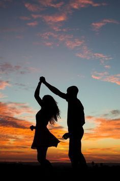 two people are dancing in front of the sunset