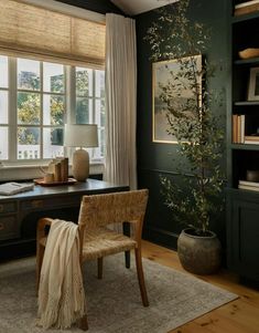 an office with green walls and wooden floors, along with a large window covered in blinds