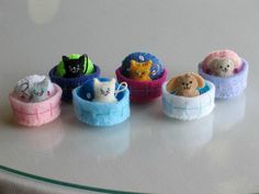 small stuffed animals are lined up in little baskets on a glass tablecloth covered surface